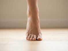 Bare foot standing on a light wooden floor indoors