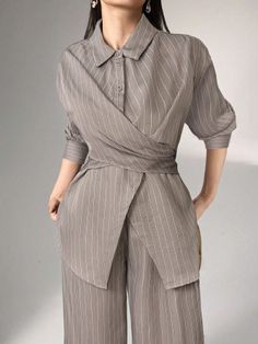 Woman in a pinstripe collared shirt and wide-leg pants with hands in pockets