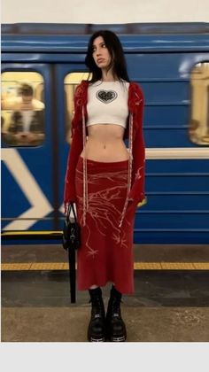 Woman in a crop top and red skirt with platform boots at a subway station