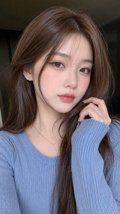 Woman with long brown hair wearing a blue sweater and butterfly earrings