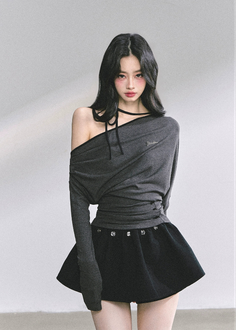Woman with black hair wearing an off-shoulder top and black skirt in a studio