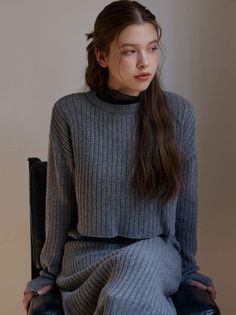 Woman with long hair wearing a gray ribbed sweater and black sheer top