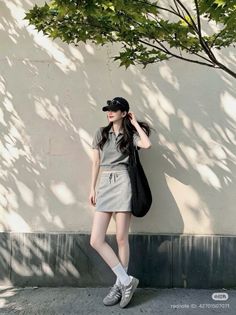 Woman in a gray polo shirt and mini skirt with a baseball cap and sunglasses