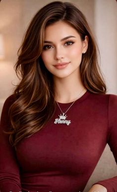 Woman with long brown hair wearing a maroon top and a necklace