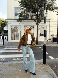 Woman with blonde hair wearing a cropped jacket and wide leg jeans on a city street