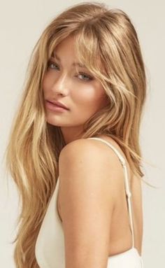 Woman with long blonde hair wearing a white top, looking over her shoulder