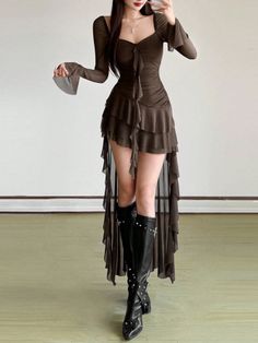 Woman in a dark ruffled dress and black studded boots posing indoors