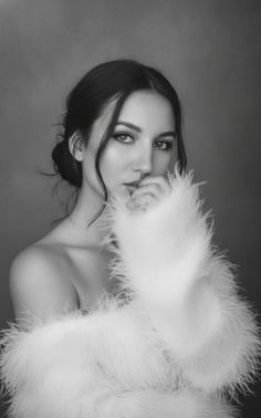 Woman in a white feather boa with dark hair in a black and white portrait