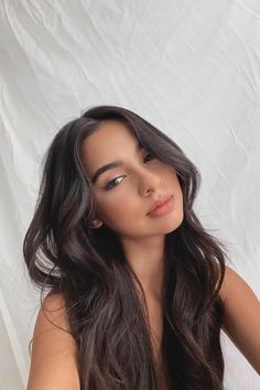 Woman with long dark wavy hair against a white background