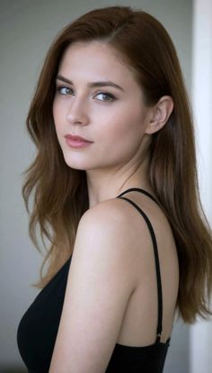 Woman with long brown hair and green eyes wearing a black top