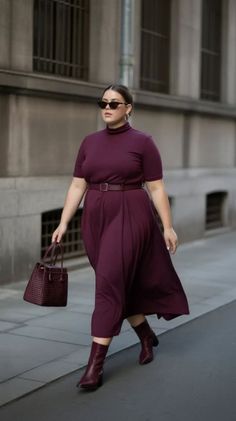 Woman in a purple midi dress and ankle boots walking on a city street