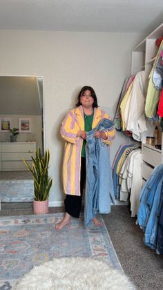 Woman in a striped coat holding jeans in a closet