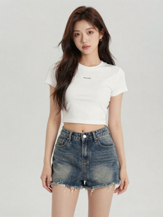 Woman with long hair wearing a white crop top and denim shorts in a studio