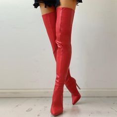 Person wearing red thigh-high boots and a short skirt indoors