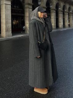 Woman in a pinstripe long coat and baseball cap on a city street