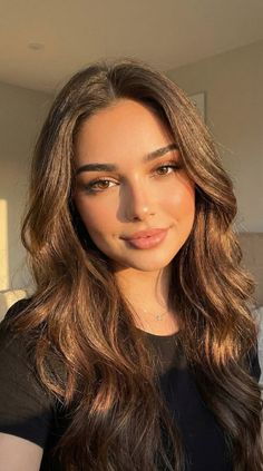 Woman with long wavy brown hair in soft golden hour lighting