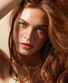 Woman with red hair and green eyes in a close-up portrait with dramatic lighting