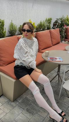 Woman in a polka dot top and black shorts sitting at an outdoor cafe