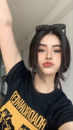 Woman with black hair and hoop earrings wearing a black t-shirt, pouting at the camera
