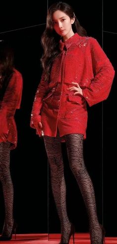 Woman in a red sequin dress and patterned tights posing against a dark background
