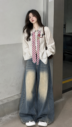 Woman with long hair wearing a striped shirt, red tie, and wide leg jeans indoors