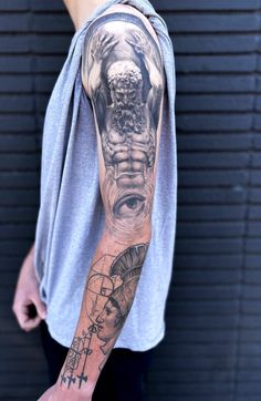 Arm with a detailed black and grey tattoo featuring a mythological figure and an eye