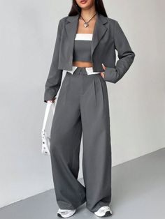 Woman in a gray cropped blazer and wide leg pants with a white crop top