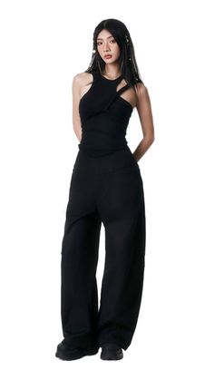 Woman in a black top and black pants posing against a white background