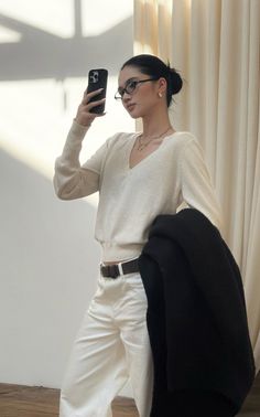 Woman with black hair and glasses taking a selfie indoors