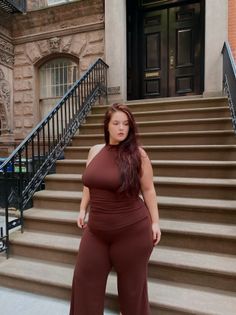 Woman with long brown hair wearing a brown outfit on outdoor stairs