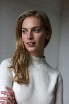 Woman with blonde hair wearing a white turtleneck sweater looking to the side