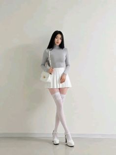 Woman in a gray turtleneck, white pleated skirt, and thigh-high stockings