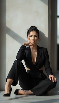 Woman in a black suit with deep cleavage and high heels posing indoors