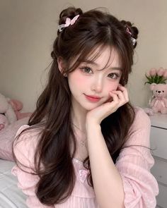 Woman with long brown hair and space buns wearing a pink top