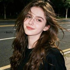 Young woman with long wavy hair smiling outdoors at night