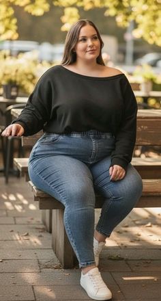 Woman with long hair and a curvy body sitting on a bench outdoors