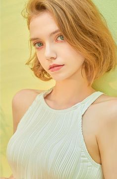 Woman with short blonde hair and green eyes wearing a light green top