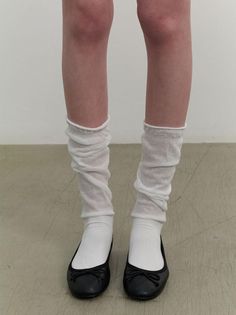 Legs wearing white socks, ruched leg warmers, and black ballet flats