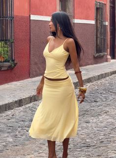 Woman in a yellow top and skirt walking on a cobblestone street