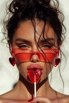 Woman with red sunglasses and a heart-shaped lollipop in a close-up shot