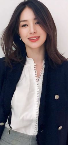 Woman with long dark hair wearing a white blouse and dark jacket
