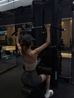 Woman in a gym wearing a sports bra and bike shorts, using a fitness machine