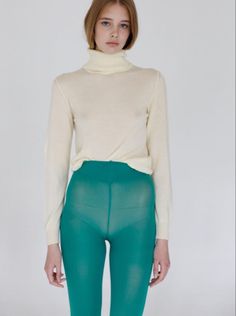 Woman in a cream turtleneck sweater and sheer green tights