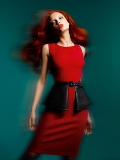 Woman with red hair in a red dress and black belt with motion blur
