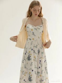 Woman in a white floral dress and a light cardigan against a white background