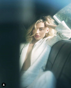Woman with blonde hair in a white blazer sitting in a car