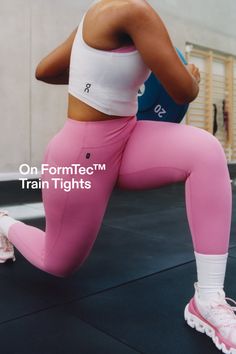 Person in pink leggings and white sports bra doing a lunge in a gym