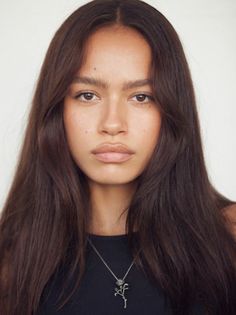 Woman with long dark hair wearing a black top and silver rose necklace