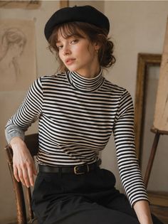 Woman in a black beret and striped turtleneck sitting indoors