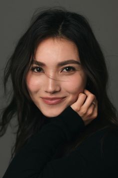 Woman with long dark hair in a black sweater, smiling at the camera